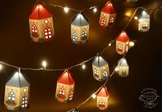 christmas lights are hanging from a string with small houses on them and lit up in the dark