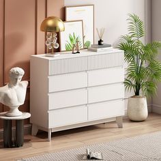 a white dresser sitting next to a potted plant