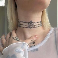 a woman wearing a chain choker with an anchor tattoo on her neck and chest