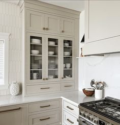 a kitchen with white cabinets and marble counter tops is pictured in this image, there are dishes on the cabinet doors