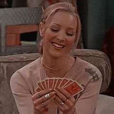 a woman sitting on a couch holding cards in her hands and smiling at the camera