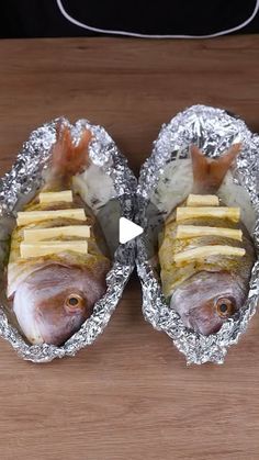 two fish are wrapped in tin foil and ready to be cooked on the stove top