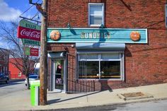 an old fashioned soda shop on the corner of a street in front of a brick building