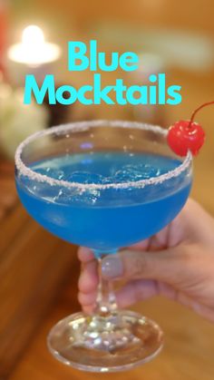 a person holding a blue cocktail in their hand