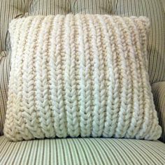 a white knitted pillow sitting on top of a couch