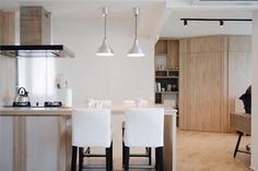 two white chairs are at the center of this modern kitchen with an island and bar stools