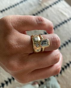 a person's hand with a gold ring on it and an emerald stone in the middle