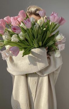 a woman is wrapped in a blanket and holding a bouquet of tulips