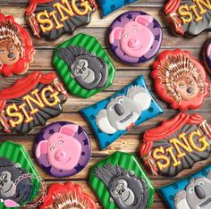 some decorated cookies that are on top of a wooden table with the words sing sing