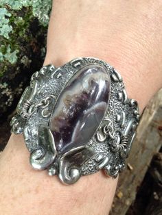 "A fine early Mexican sterling silver cuff bracelet with lace agate. This heavy sterling cuff features a complex lace agate cabochon (23mm x 45mm) with colors in the range of purple, grey, and white. The stone almost looks to have interior crystals and looks more purple in sunlight. Next to the stone on either side are two little dangles made from rings. These shake and move when you walk and make a little click click rattle. Bracelet is easy on and off and secure for wearing. Hand etched to say Unique Handmade Agate Cuff Bracelet, Handmade Unique Agate Cuff Bracelet, Handmade Agate Cuff Bracelet Unique Style, Artisan Silver Bracelet With Cabochon, Silver Artisan Bracelet With Cabochon, Unique Oval Gemstone Cuff Bracelet, Silver Cuff Bracelet With Cabochon, Silver Sterling Silver Cuff Bracelet With Cabochon, Unique Silver Cuff Bracelet With Cabochon