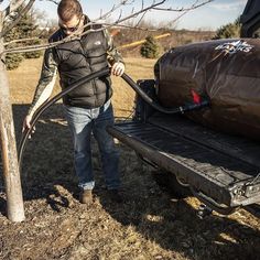 a man is pulling a trailer with a bag on it and another truck behind him