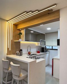 a modern kitchen with white counter tops and bar stools next to the stove top