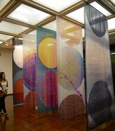 the woman is walking past some colorful art on display in an office building with wood flooring