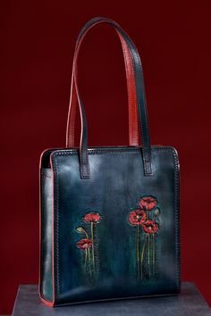 "Hand tooled leather bag with red poppies. The bag has very interested peacock blue color wtih dark and light tints. When dyeing  the leather, we set the shades of several colors. Combining this background with hand tooled  red poppies produces an interesting and beautiful texture. The bag closes with a zipper.  Whole bag is hand stitched (including shuolder straps). Shoulder straps made from two layers leather which are connected with hand stitching. Upper layer made from thick and qualitative leather and backside from goatskin. The liner of the bag is from red \"Greta\" lining fabric.  The product is coated with finish wax, which prolongs moisture protection and contamination. Тhis is a very comfortable and spacious bag for any occasion. It looks elegant and casual at same time. 5 leathe Hand-painted Leather Tote Shoulder Bag, Hand Painted Leather Tote Shoulder Bag, Hand Painted Blue Leather Bags, Elegant Hand Painted Rectangular Bag, Elegant Hand Painted Rectangular Bags, Luxury Hand-painted Leather Bags, Luxury Hand Painted Bags For Travel, Luxury Hand Painted Leather Bags, Luxury Hand-painted Travel Bag