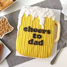 there is a cake that says cheers to dad on the table next to other foods