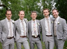 a group of men standing next to each other wearing suits and ties on the grass