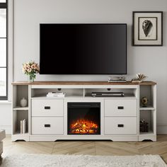 a flat screen tv sitting on top of a white entertainment center next to a fire place