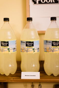 three gallon jugs of lemonade on a shelf in a store or office setting