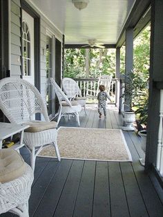 a little boy that is standing on a porch with some chairs in front of him