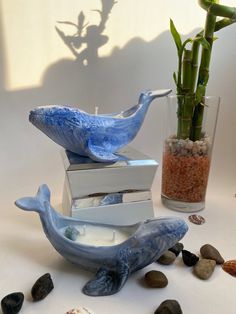 two blue whale figurines sitting on top of each other next to some rocks