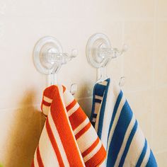 three towels hanging on hooks in a bathroom