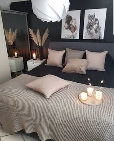 a bed with two candles and pictures on the wall above it in a bedroom setting