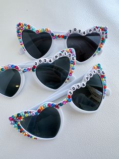 This listing is for one pair of bespoke heart sunglasses embellished by hand. Personalized sunnies are perfect gifts for moms, daughters, graduates, and brides, and are great for festivals, concerts, birthday parties, and team pride! PLEASE NOTE: This item is made by hand, which means that embellishments may vary from the image. I use a combination of high quality glass rhinestones and resin flat-back pearls, along with other eclectic embellishments like flowers, butterflies, and snakes. Due to Pride Sunglasses, Sunglasses Ideas, Girls Sunglasses, Beaded Sunglasses, Gifts For Moms, Hair Business, Dance Recital, Gold Text, Heart Sunglasses