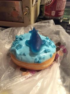 a blue frosted doughnut with a shark fin on it sitting on plastic wrap