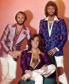 the bee gees posing for a photo in their purple suits and white pants, with one man sitting on a green chair