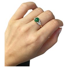 a woman's hand holding an emerald and diamond ring