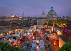 an outdoor dining area with tables and chairs on top of a roof at night time