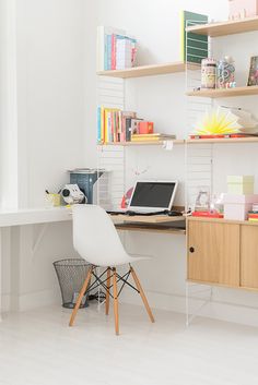 a desk with a laptop computer on top of it next to a book shelf filled with books