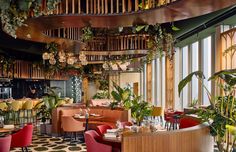 the interior of a restaurant with plants hanging from the ceiling and colorful chairs on the tables