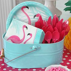 a blue bucket filled with pink flamingos on top of a table next to pineapples