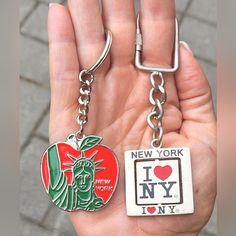 two new york and i love ny keychains in the palm of someone's hand