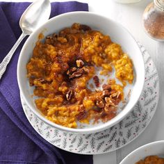 two bowls filled with food sitting on top of a table next to silver spoons