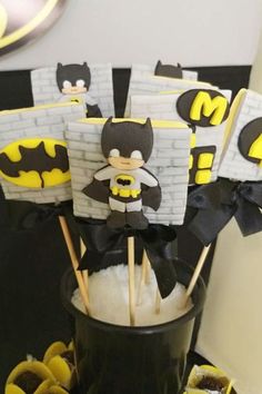 batman cake pops are in a bucket with marshmallows and black bow ties