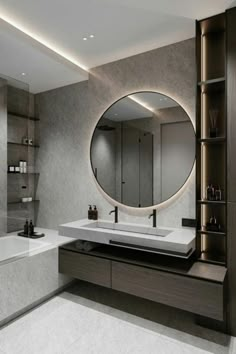 a bathroom with a large round mirror above the sink and bathtub in front of it