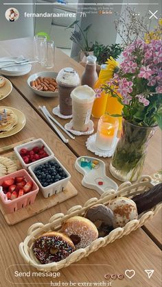 a wooden table topped with plates and bowls filled with food next to vases full of flowers