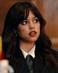 a close up of a person wearing a suit and tie with long dark brown hair