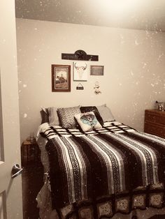 a bedroom with a bed, dresser and pictures on the wall above it in black and white