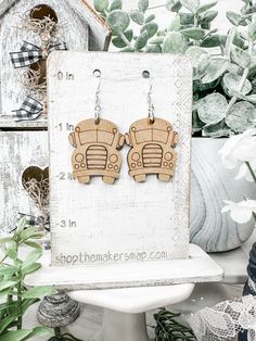 a pair of wooden earrings sitting on top of a white pedestal next to potted plants