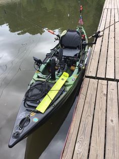 a kayak tied up to a dock with fishing gear on it's side