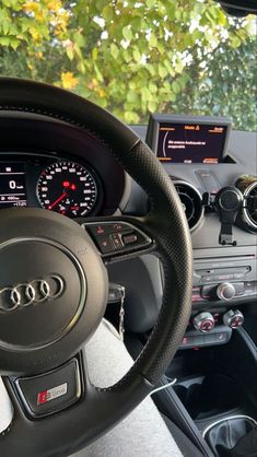 the steering wheel and dashboard of a car with trees in the backgrouund