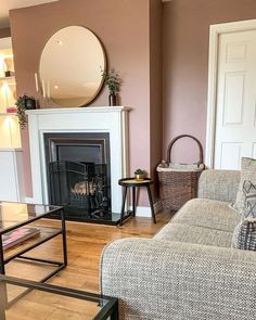 a living room filled with furniture and a fire place under a mirror on the wall