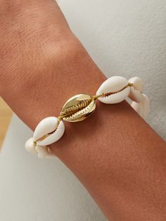 Leave it to Tohum to make jewelry that reminds us of our favorite sandy getaways. This bracelet strings together white cowrie shells and a single gold-plated one at its center and has an adjustable slider, so it'll fit any wrist comfortably. Wear yours with the coordinating necklace in our edit. Cowrie Shell Jewelry, Latest Bracelets, Wave Bracelet, Shell Bracelet, Gold Plated Bracelets, Cowrie Shell, Diamonds And Gold, Shell Jewelry, Blue Bracelet