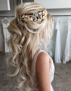 a woman with long blonde hair wearing a flowered headpiece in front of her wedding dress