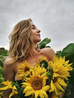 a woman holding sunflowers in her hands