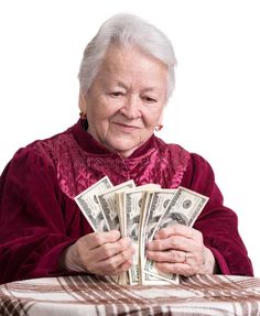 an old woman holding money in her hands while sitting at a table with a white background