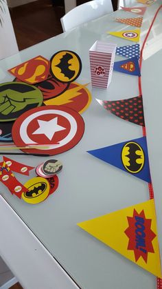 the table is covered with paper cutouts and superhero themed pennants, including captain america's shield